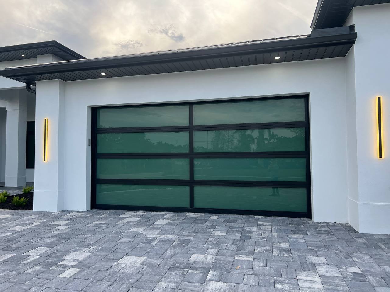 AA Impact Series 1800 flagship black-frame green-glass impact garage door on a luxury South Florida home.